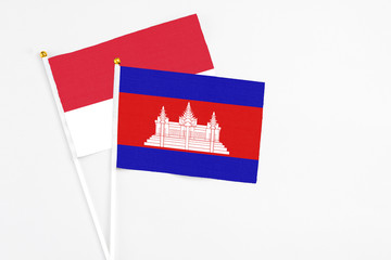 Cambodia and Monaco stick flags on white background. High quality fabric, miniature national flag. Peaceful global concept.White floor for copy space.