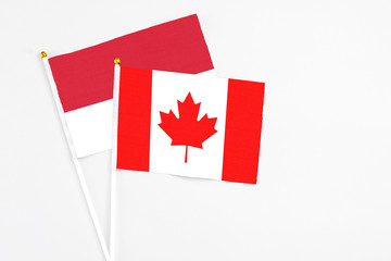 Fototapeta na wymiar Canada and Monaco stick flags on white background. High quality fabric, miniature national flag. Peaceful global concept.White floor for copy space.