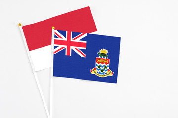 Fototapeta premium Cayman Islands and Monaco stick flags on white background. High quality fabric, miniature national flag. Peaceful global concept.White floor for copy space.