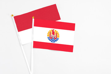 French Polynesia and Monaco stick flags on white background. High quality fabric, miniature national flag. Peaceful global concept.White floor for copy space.