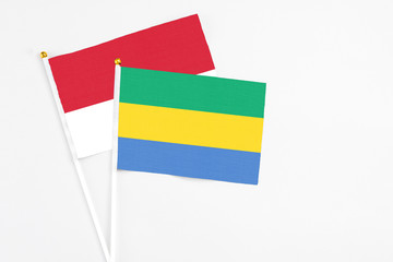 Gabon and Monaco stick flags on white background. High quality fabric, miniature national flag. Peaceful global concept.White floor for copy space.
