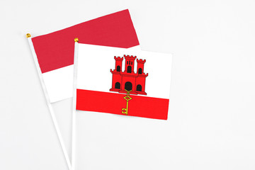 Gibraltar and Monaco stick flags on white background. High quality fabric, miniature national flag. Peaceful global concept.White floor for copy space.
