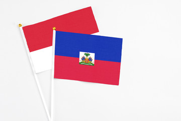 Haiti and Monaco stick flags on white background. High quality fabric, miniature national flag. Peaceful global concept.White floor for copy space.