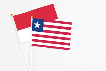 Liberia and Monaco stick flags on white background. High quality fabric, miniature national flag. Peaceful global concept.White floor for copy space.