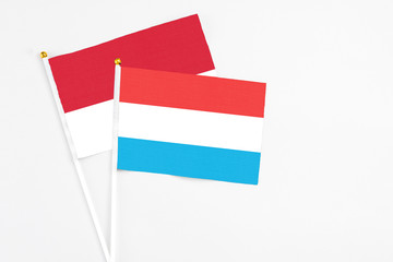 Luxembourg and Monaco stick flags on white background. High quality fabric, miniature national flag. Peaceful global concept.White floor for copy space.