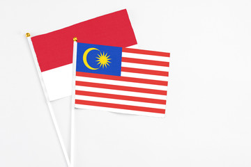 Malaysia and Monaco stick flags on white background. High quality fabric, miniature national flag. Peaceful global concept.White floor for copy space.