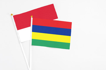 Mauritius and Monaco stick flags on white background. High quality fabric, miniature national flag. Peaceful global concept.White floor for copy space.