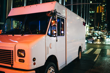 White van of delivery shipping service parked on road in downtown at night. postal truck body of...