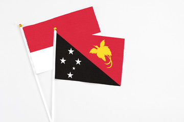 Papua New Guinea and Monaco stick flags on white background. High quality fabric, miniature national flag. Peaceful global concept.White floor for copy space.
