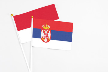 Serbia and Monaco stick flags on white background. High quality fabric, miniature national flag. Peaceful global concept.White floor for copy space.