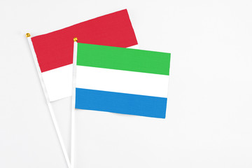 Sierra Leone and Monaco stick flags on white background. High quality fabric, miniature national flag. Peaceful global concept.White floor for copy space.
