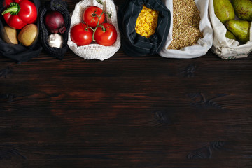 Lots of fresh organic food in plastic free and eco friendly bags on wooden table. Zero waste food shopping. Copy space