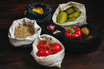 Lots of fresh organic food in plastic free and eco friendly bags on wooden table. Zero waste food shopping. Copy space