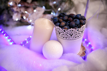 Christmas scenery white candle on the side and snow ball near white bucket with acorns