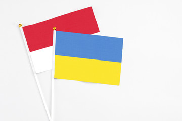 Ukraine and Monaco stick flags on white background. High quality fabric, miniature national flag. Peaceful global concept.White floor for copy space.