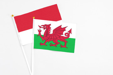 Wales and Monaco stick flags on white background. High quality fabric, miniature national flag. Peaceful global concept.White floor for copy space.