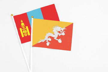 Bhutan and Mongolia stick flags on white background. High quality fabric, miniature national flag. Peaceful global concept.White floor for copy space.