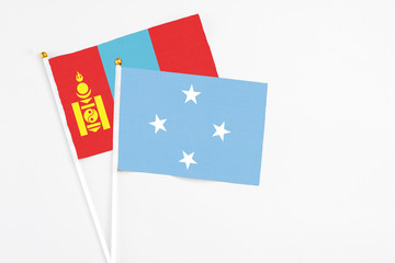 Micronesia and Mongolia stick flags on white background. High quality fabric, miniature national flag. Peaceful global concept.White floor for copy space.