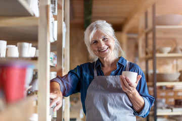 Portrait of senior female pottery artist in her art studio