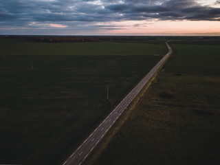 Road to horizont at Lithuania from drone, space for text, dark photo.