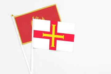 Guernsey and Montenegro stick flags on white background. High quality fabric, miniature national flag. Peaceful global concept.White floor for copy space.