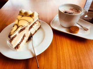 Eierlikörtortenstück mit Cappuccino auf dem Holztisch