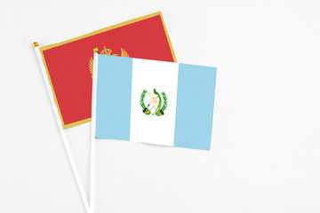 Guatemala and Montenegro stick flags on white background. High quality fabric, miniature national flag. Peaceful global concept.White floor for copy space.