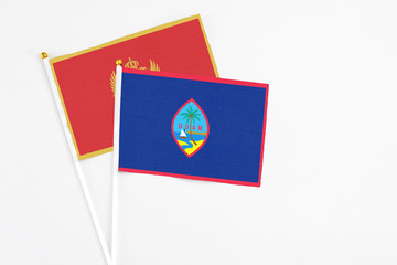 Guam and Montenegro stick flags on white background. High quality fabric, miniature national flag. Peaceful global concept.White floor for copy space.