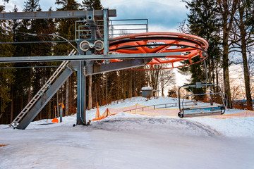 A chair lift and its elements close up, skiers are sitting in chairs.