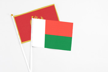 Madagascar and Montenegro stick flags on white background. High quality fabric, miniature national flag. Peaceful global concept.White floor for copy space.