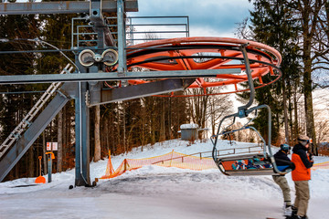 A chair lift and its elements close up, skiers are sitting in chairs.