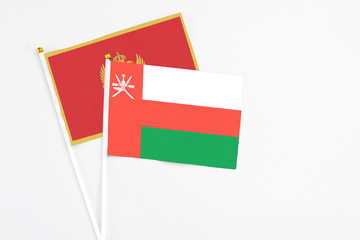 Oman and Montenegro stick flags on white background. High quality fabric, miniature national flag. Peaceful global concept.White floor for copy space.