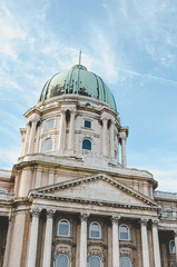 Cupola of the Buda Castle in Budapest, Hungary on vertical photo. Bottom view against the light sky. Historical castle and palace complex of the Hungarian kings. Facade with pillars and cupola