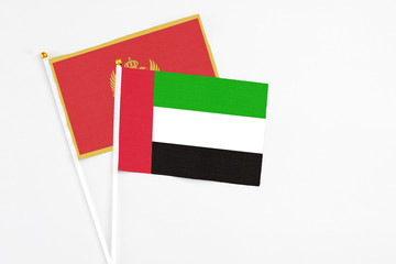 United Arab Emirates and Montenegro stick flags on white background. High quality fabric, miniature national flag. Peaceful global concept.White floor for copy space.