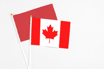 Fototapeta na wymiar Canada and Morocco stick flags on white background. High quality fabric, miniature national flag. Peaceful global concept.White floor for copy space.