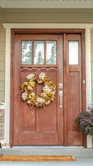Fototapeta na wymiar Vertical Front door with dried flower wreath day