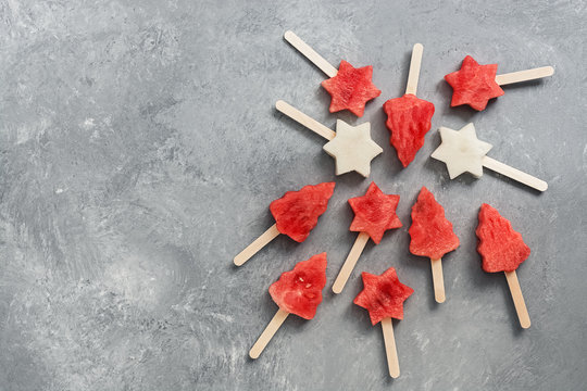Watermelon and melon popsicles. Summer fruit dessert. Ice cream made from fruits in the shape of a Christmas tree and a star.