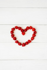 Heart of fresh organic berries on a white wooden plank background