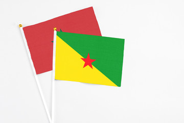 French Guiana and Morocco stick flags on white background. High quality fabric, miniature national flag. Peaceful global concept.White floor for copy space.