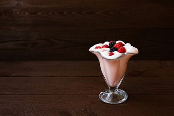 Fresh milk raspberry cocktail with fresh raspberries and blackberries on a brown wooden background. The concept of soft drinks in the summer menu