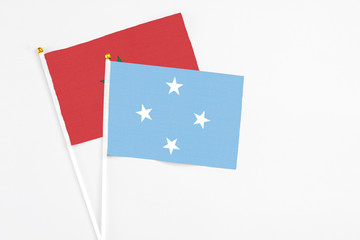 Micronesia and Morocco stick flags on white background. High quality fabric, miniature national flag. Peaceful global concept.White floor for copy space.