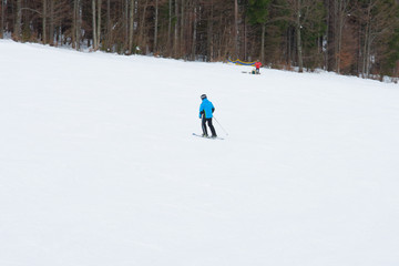 Skiers descend on the slopes of the Carpathian slopes and mountains, on the background are picturesque scenery and ski slopes.