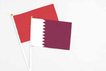 Qatar and Morocco stick flags on white background. High quality fabric, miniature national flag. Peaceful global concept.White floor for copy space.