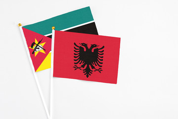 Albania and Mozambique stick flags on white background. High quality fabric, miniature national flag. Peaceful global concept.White floor for copy space.