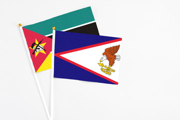American Samoa and Mozambique stick flags on white background. High quality fabric, miniature national flag. Peaceful global concept.White floor for copy space.