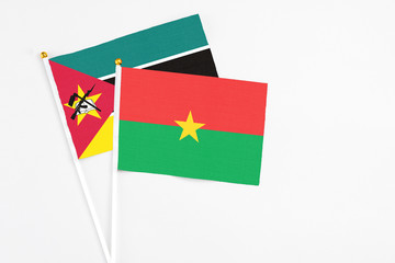 Burkina Faso and Mozambique stick flags on white background. High quality fabric, miniature national flag. Peaceful global concept.White floor for copy space.