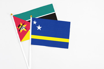 Curacao and Mozambique stick flags on white background. High quality fabric, miniature national flag. Peaceful global concept.White floor for copy space.