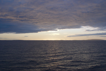 Fototapeta premium Image of the sunset hidden by clouds over the sea