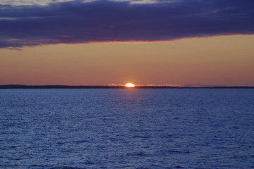Image of the sun setting in the sea behind the island