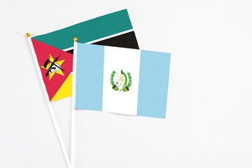 Guatemala and Mozambique stick flags on white background. High quality fabric, miniature national flag. Peaceful global concept.White floor for copy space.